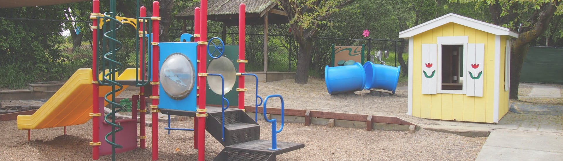 Playground with a yellow slide, blue climbing structure, and yellow playhouse