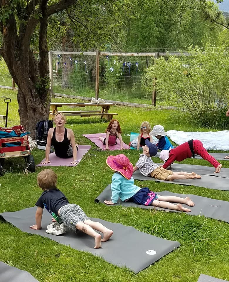 Adult and children doing yoga poses outdoors on mats