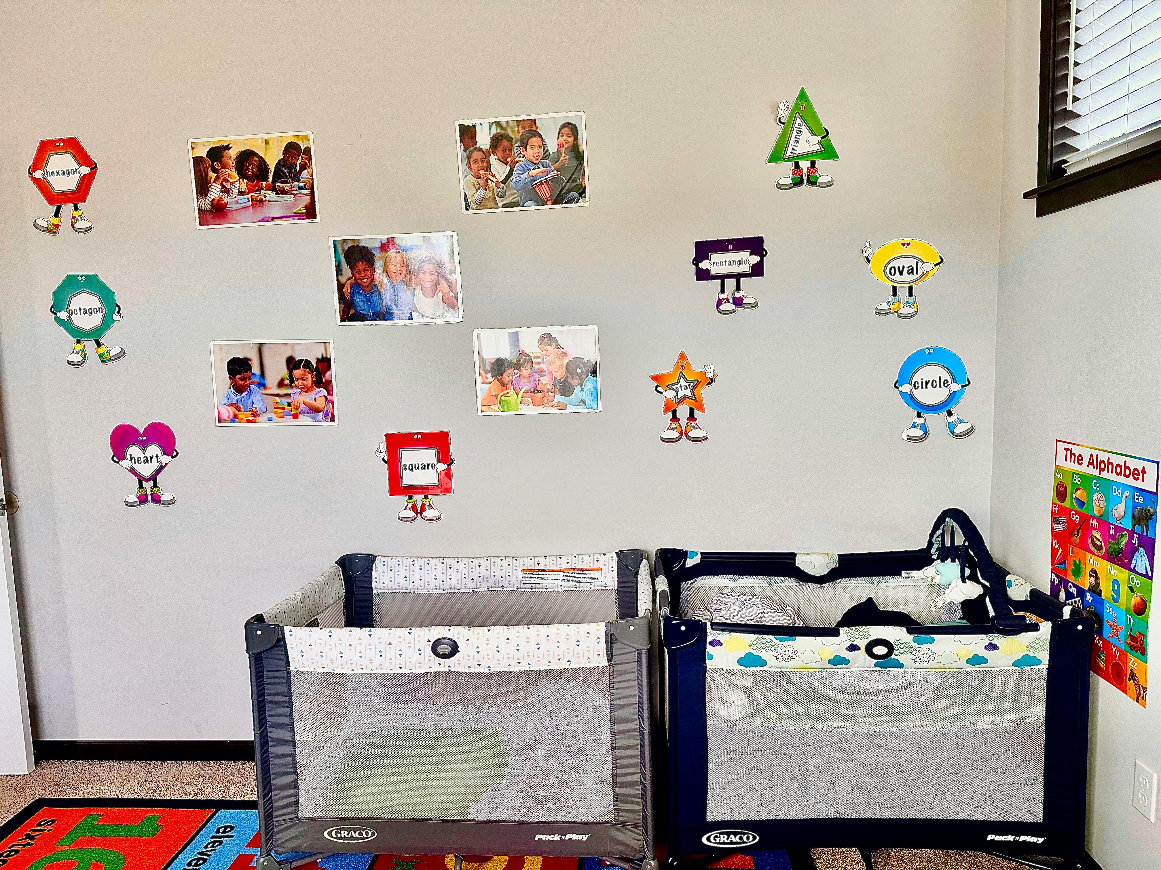 Two cribs in a room with photos and shapes on the wall