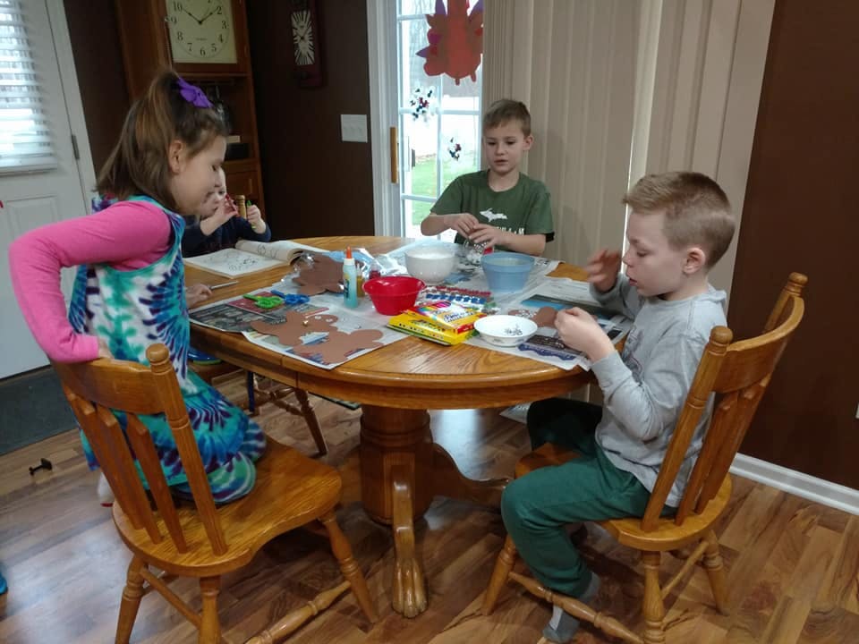 Three children sitting at a table doing crafts