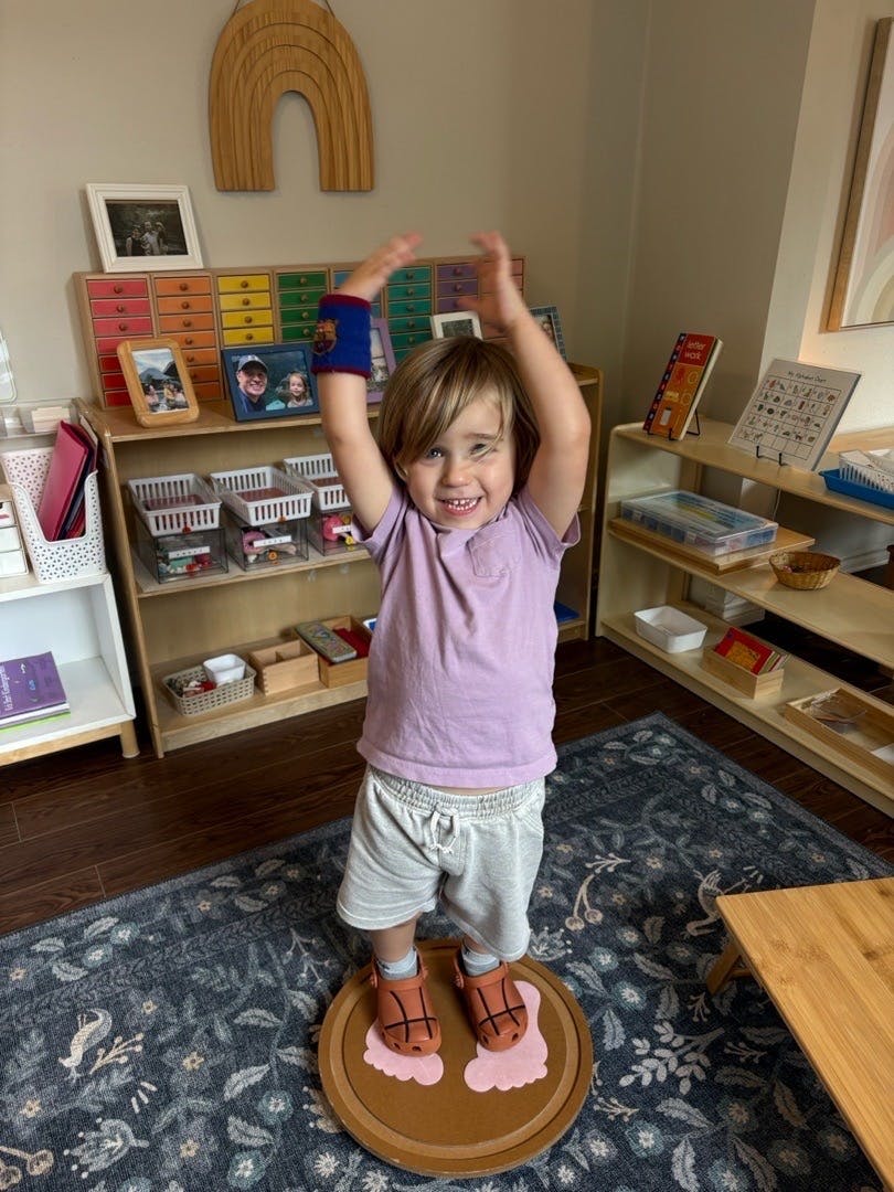 Child standing on a balance board with arms raised in a room