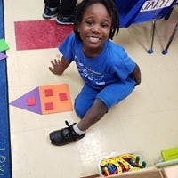 Child sitting on floor next to building blocks