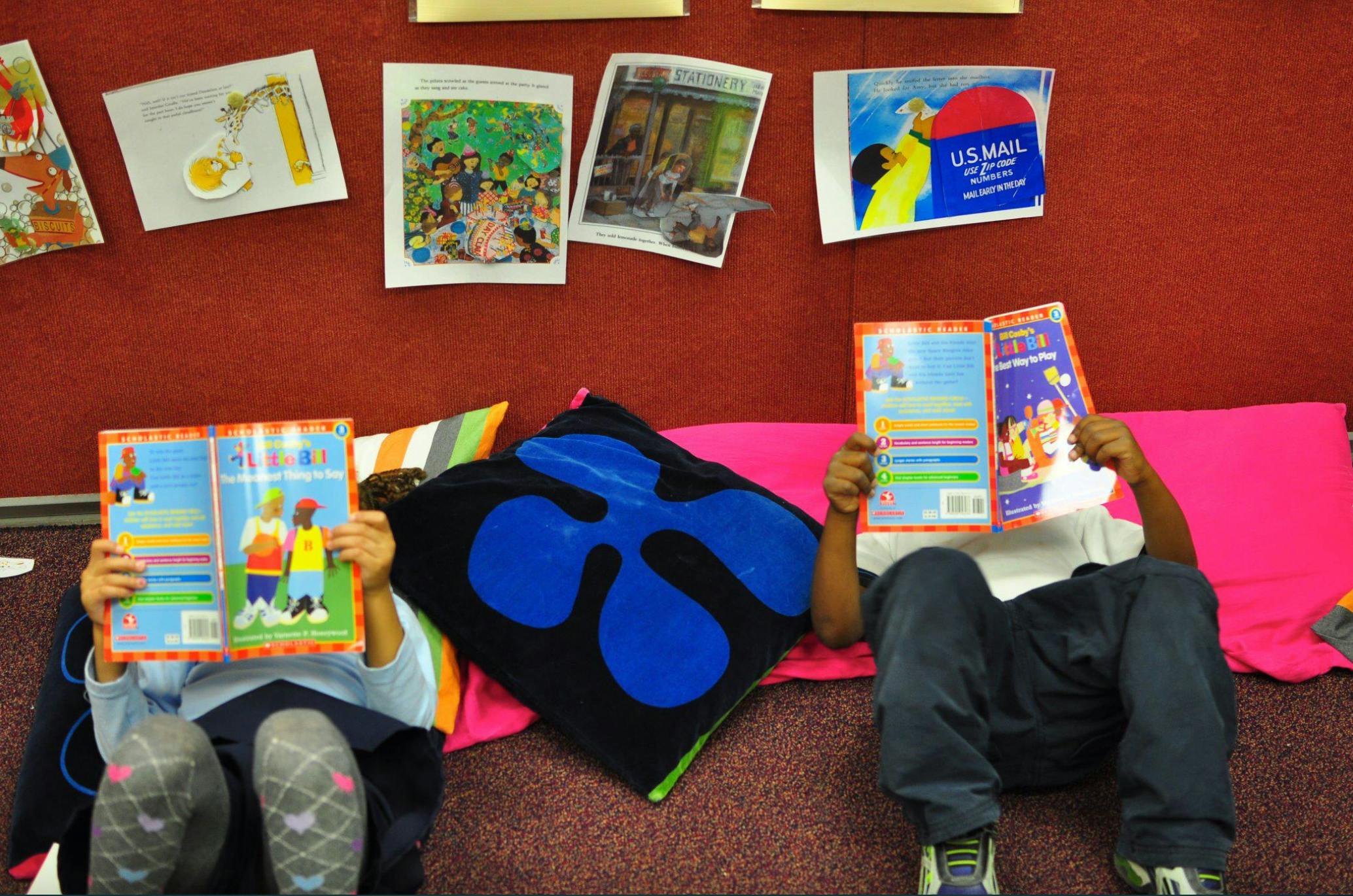 Two children sitting on the floor reading books