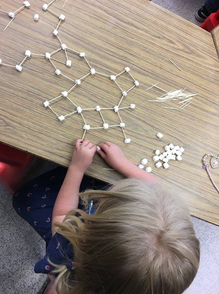 Child building a structure with toothpicks and marshmallows