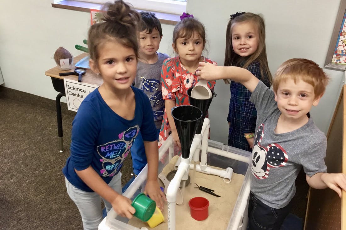 Children playing with a water table in a classroom