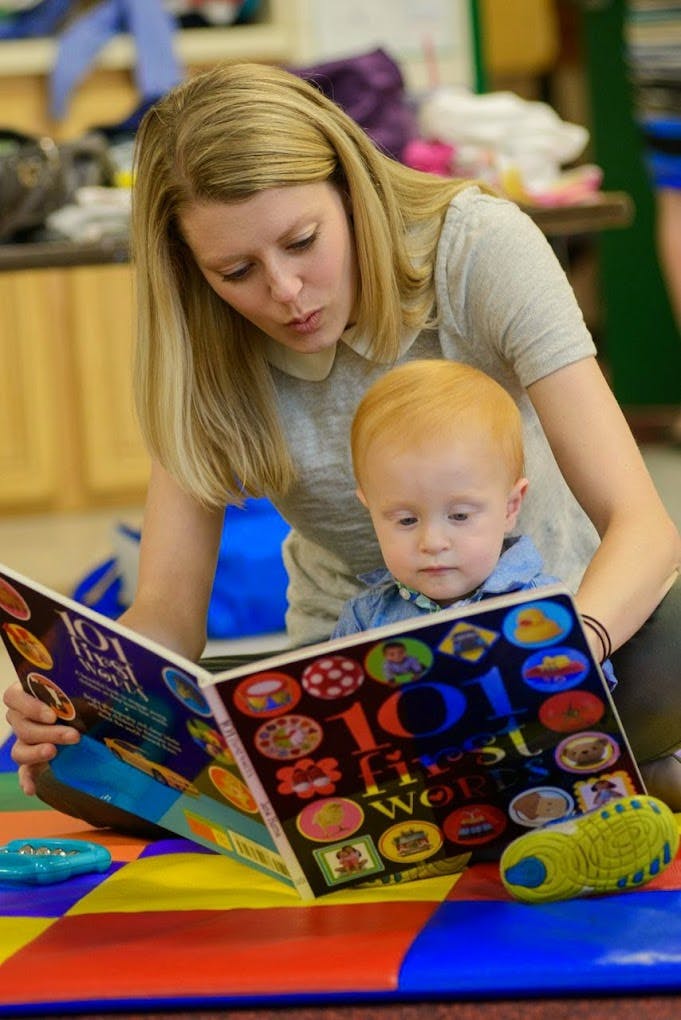 Person reading a book to a child in a classroom