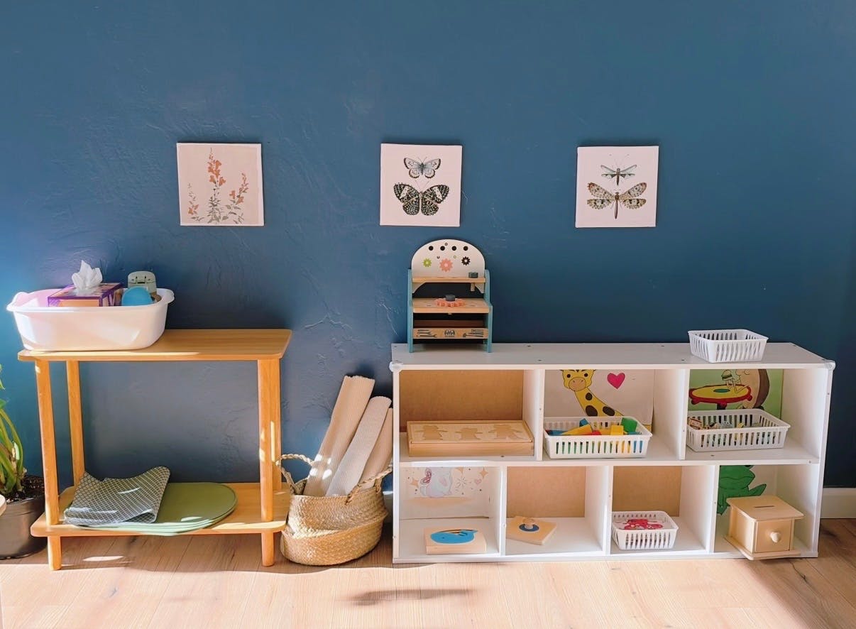 Wooden table with a basin next to a white cubby shelf filled with toys