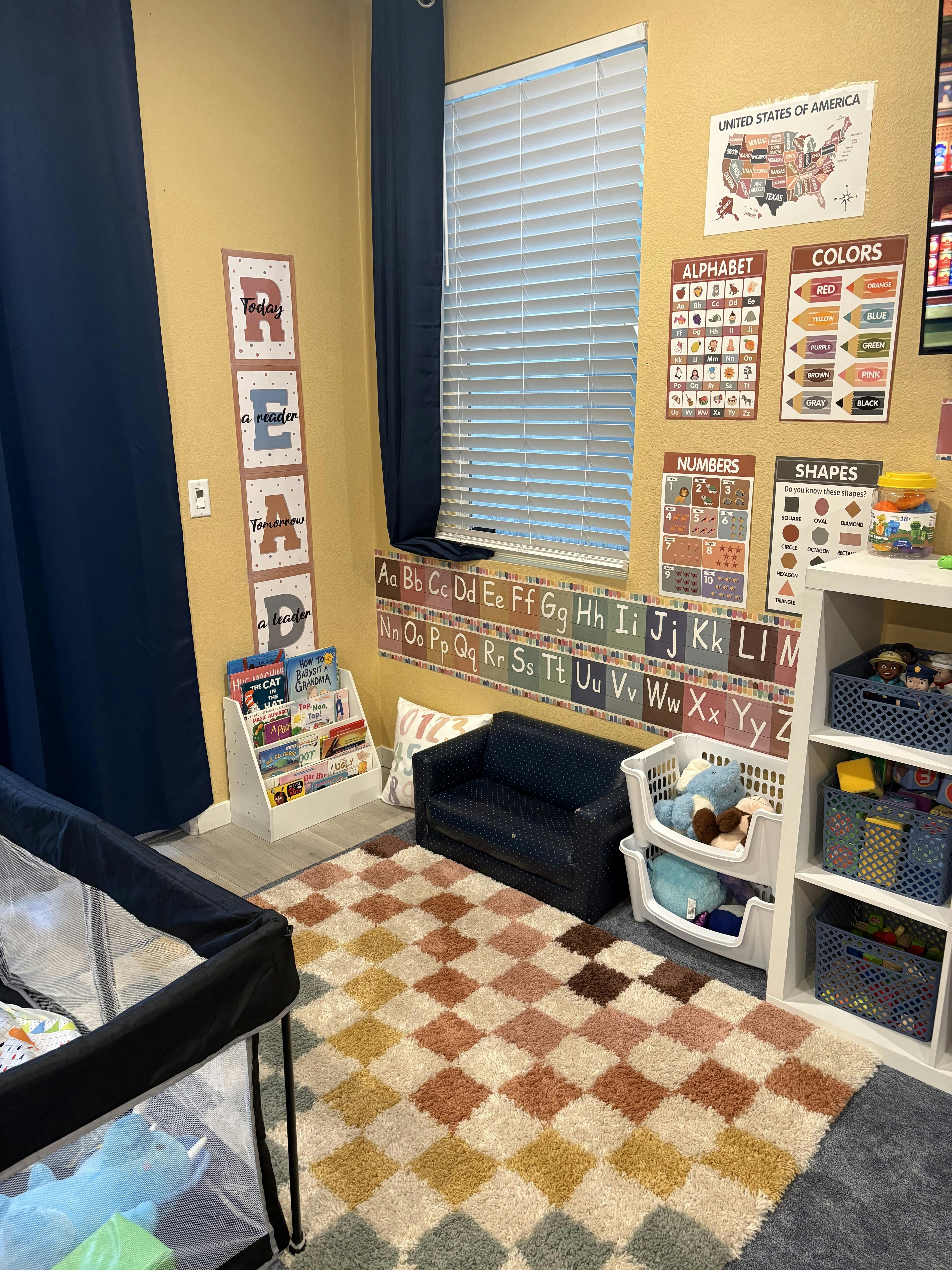 Child's room with educational posters, a small couch, playpen, and toys