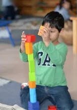 Child building a tall tower with colorful blocks