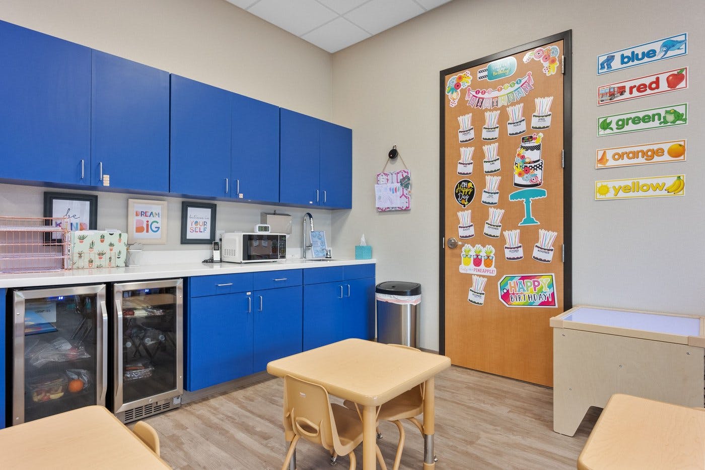 Classroom kitchen area with blue cabinets and child-sized tables