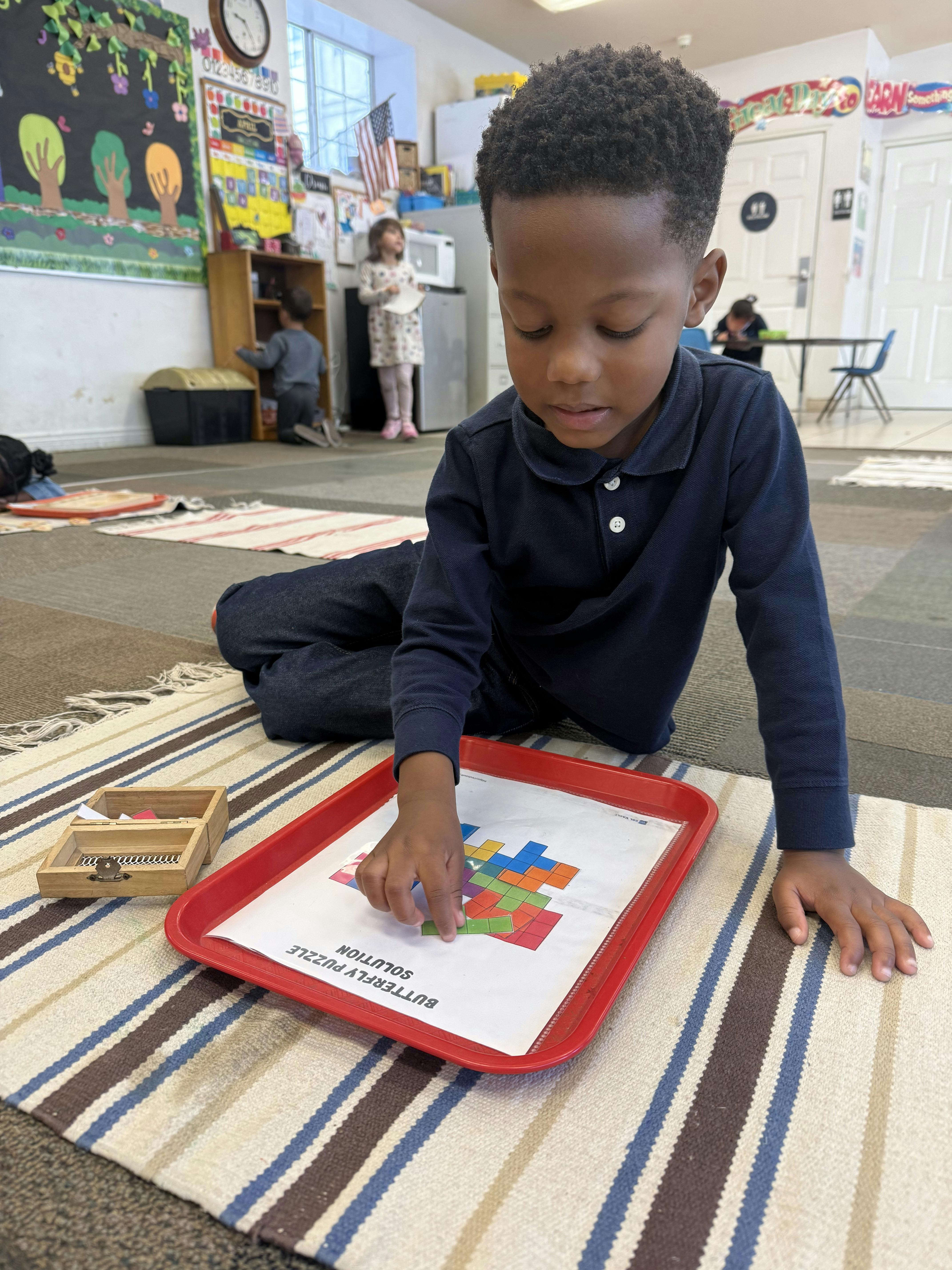 Child on the floor playing with a puzzle on a red tray