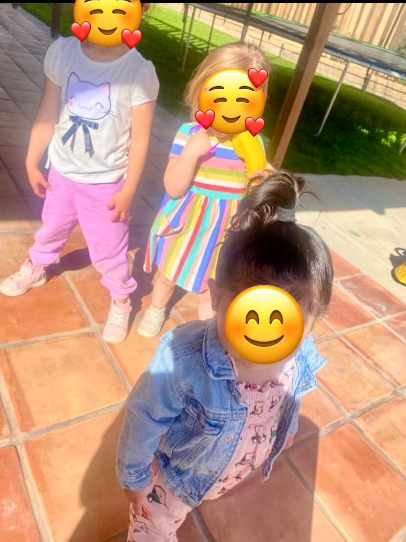 Three children standing on a tiled patio outdoors