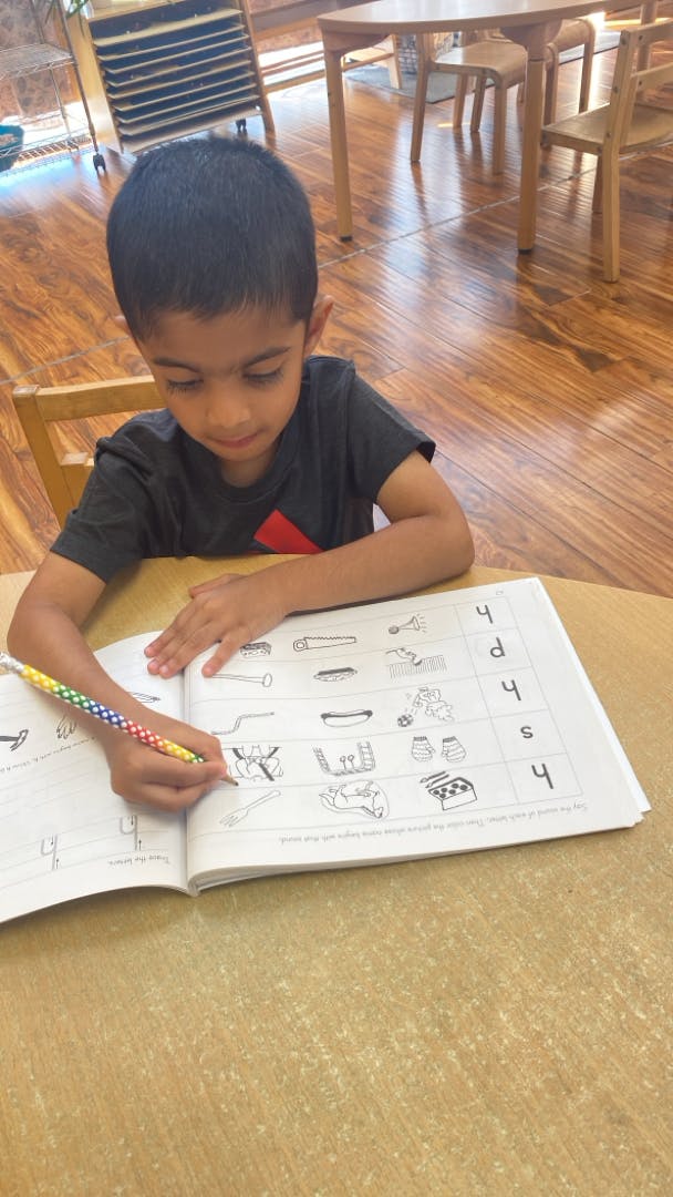 Child writing in a workbook with a pencil