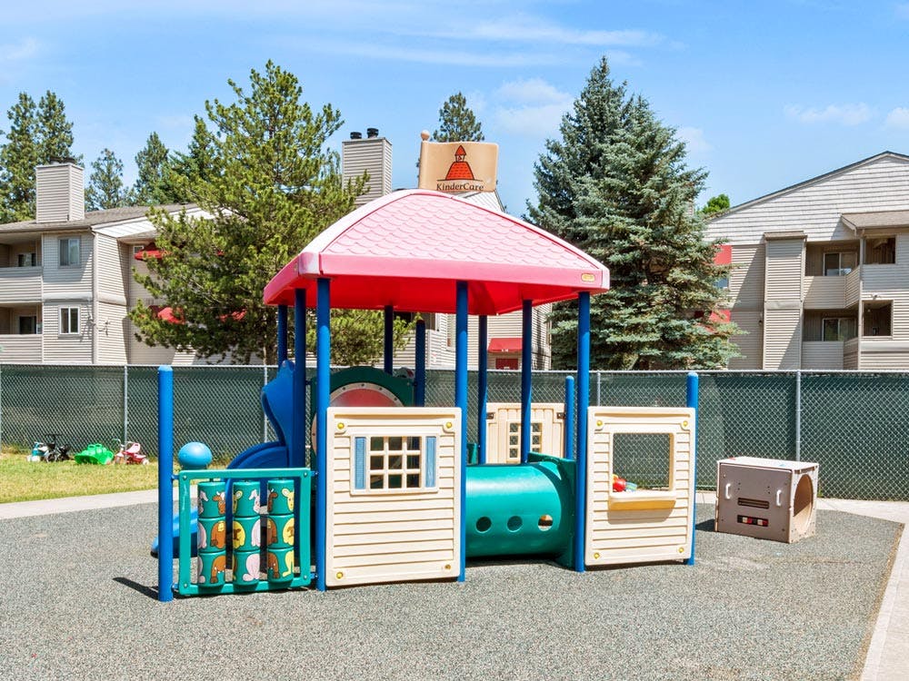A colorful plastic playground structure with a sign that reads KinderCare