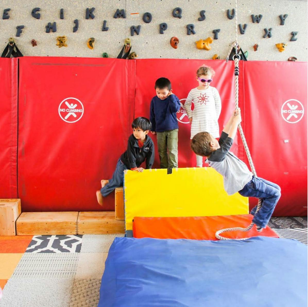 Children playing on soft blocks and a rope swing in a play area