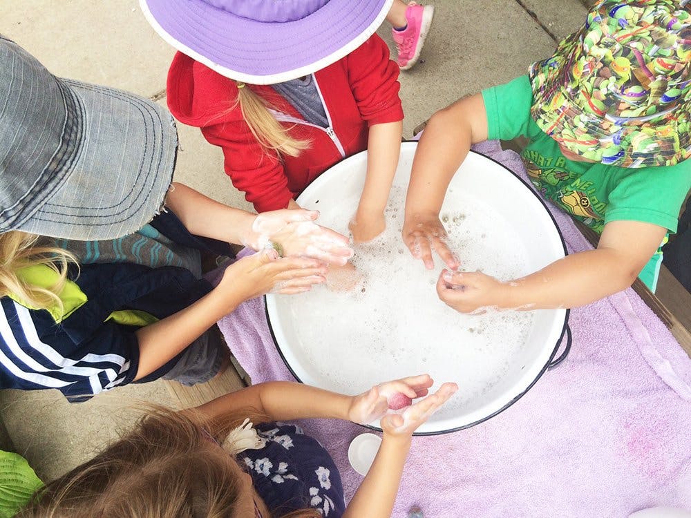 Children washing hands in a large basin of soapy water