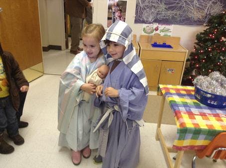 Two children in costumes, one holding a doll