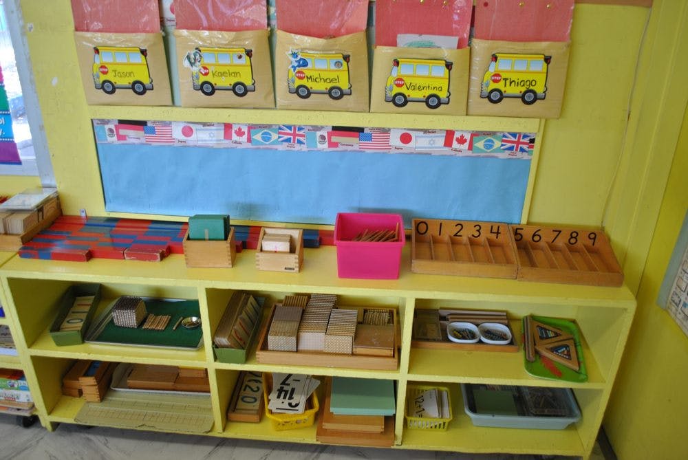 Classroom shelving unit with learning materials and bus-themed pockets