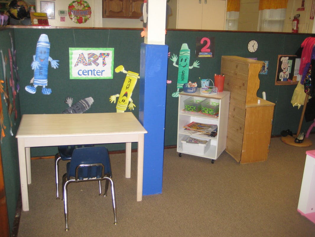 Classroom art center with a table, chairs, and crayon decorations