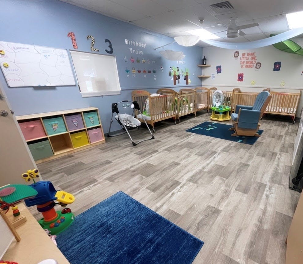 Nursery room with multiple cribs, a rocking chair, and play mats