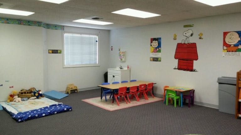 Children's classroom with small tables and chairs, and a sleeping mat