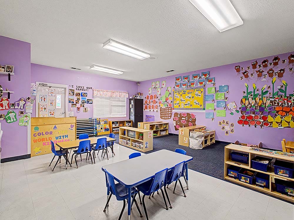 Empty colorful preschool classroom with small tables and chairs