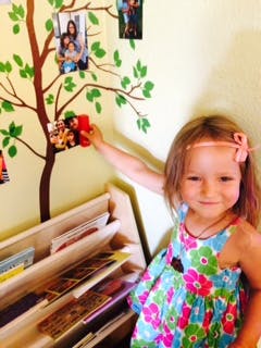 Child placing a photo on a tree decal on a wall