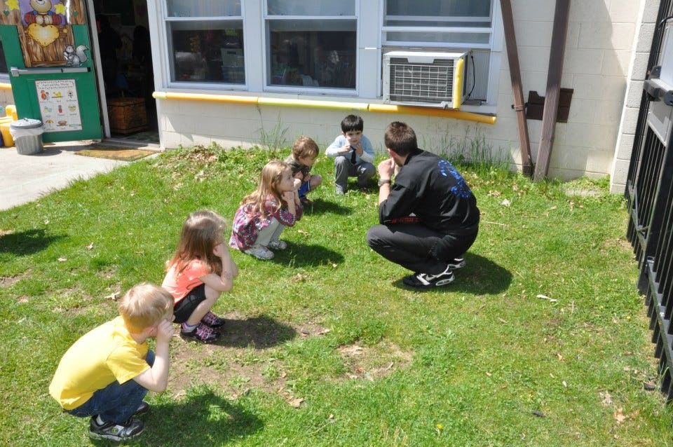 Adult and children crouching on grass