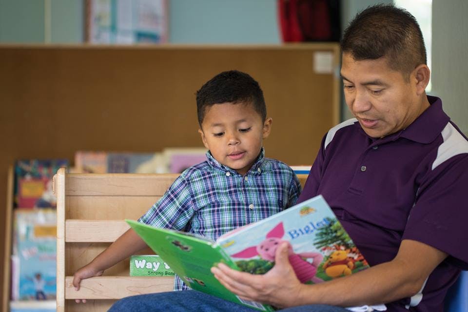 Adult and child reading a book together