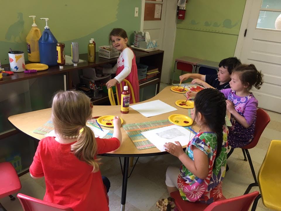 Children sitting at a table with papers and plates
