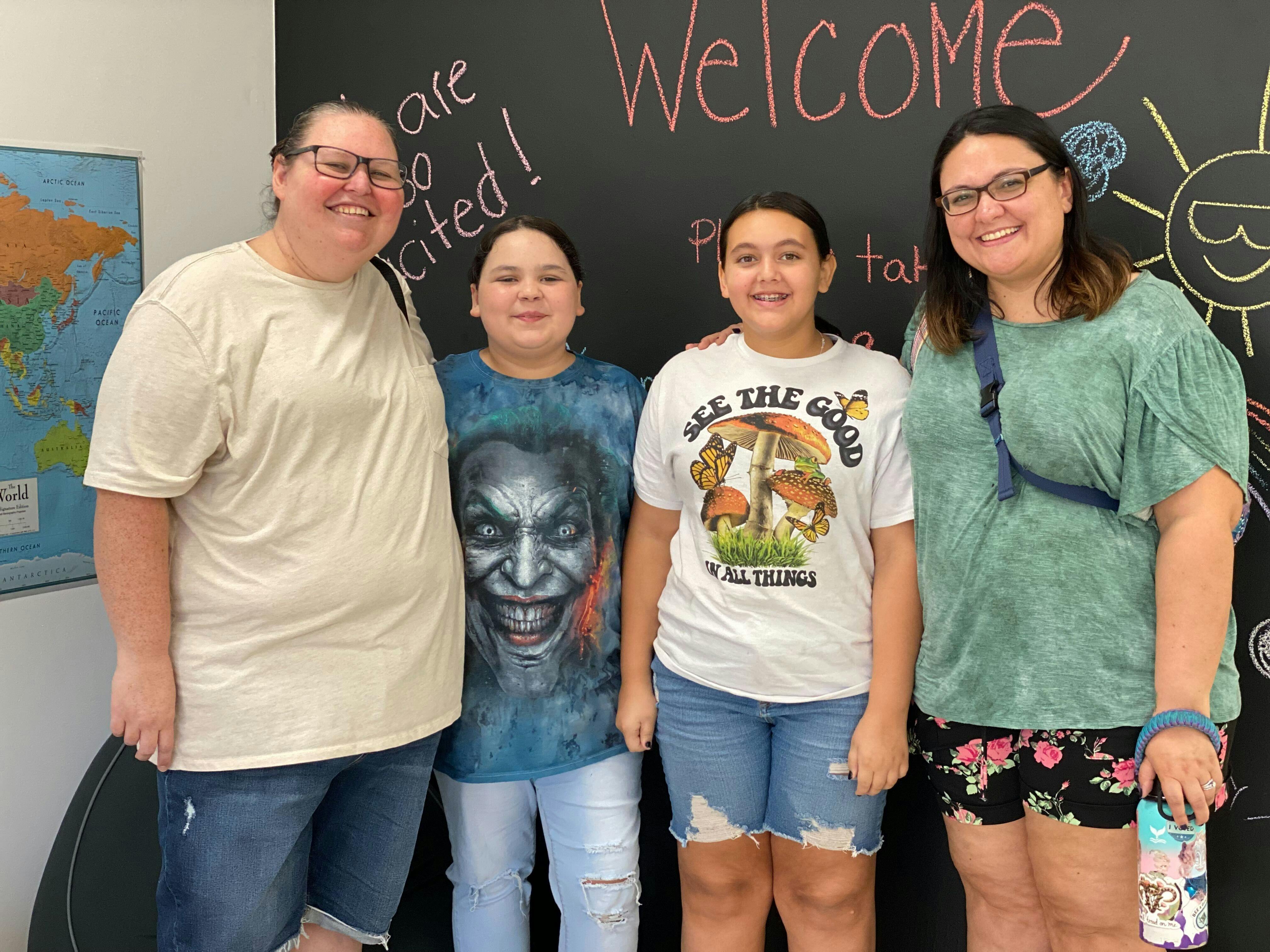 Two adults and two children standing in front of a chalkboard