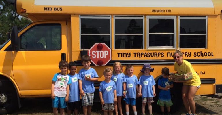 Children and an adult standing in front of a school bus