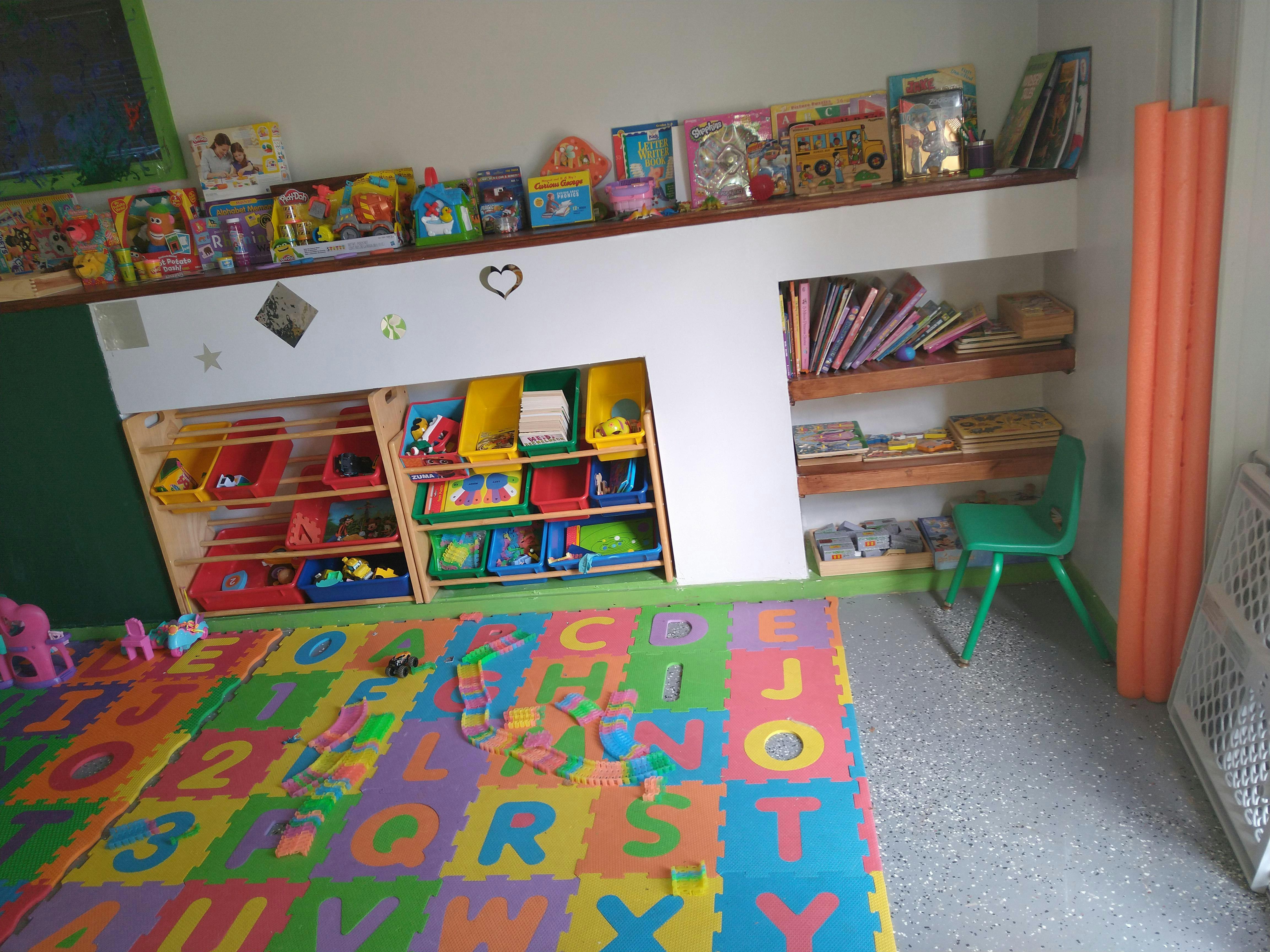 Playroom with alphabet mat, toy shelves, and books
