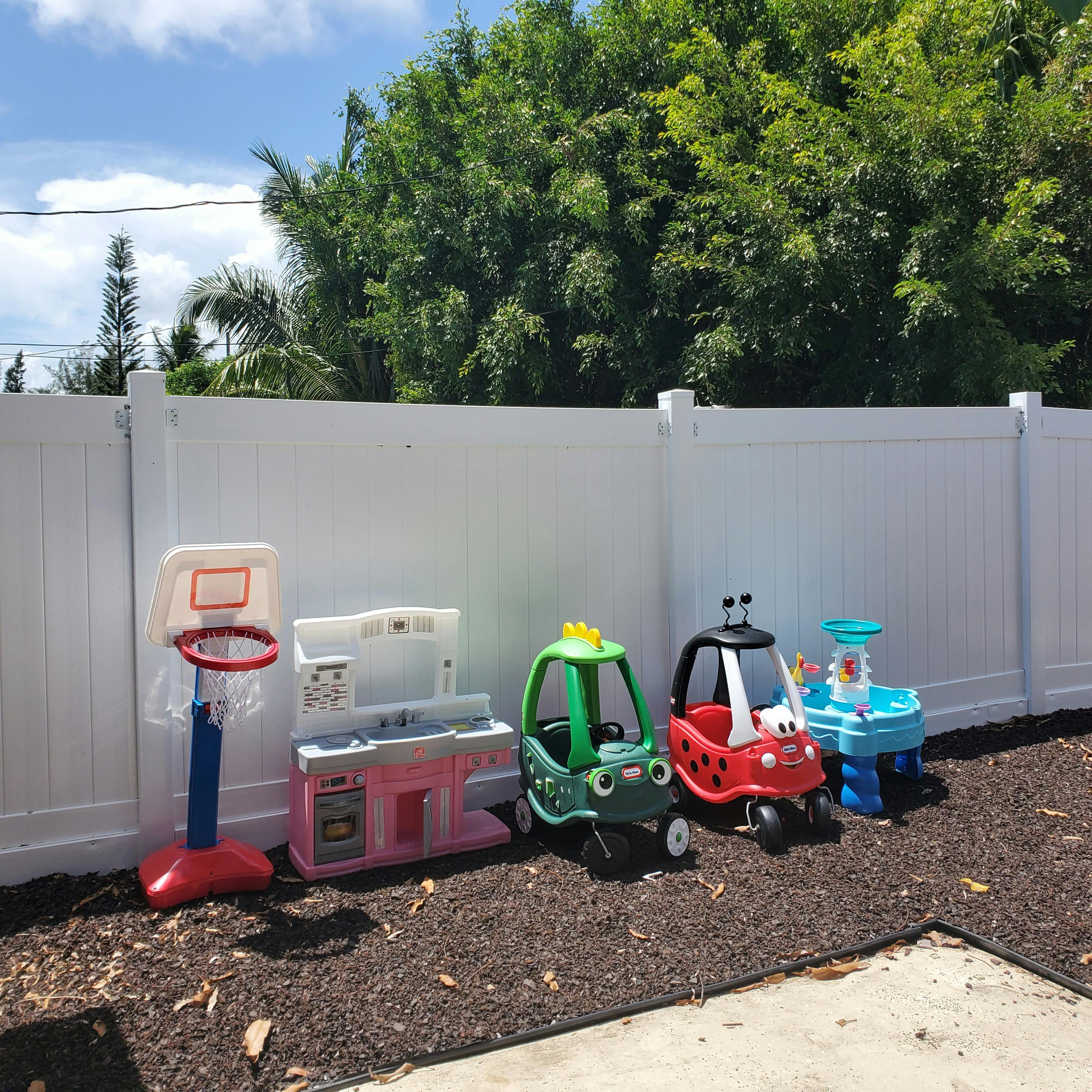 Children's toys including a basketball hoop, play kitchen, and ride-on cars