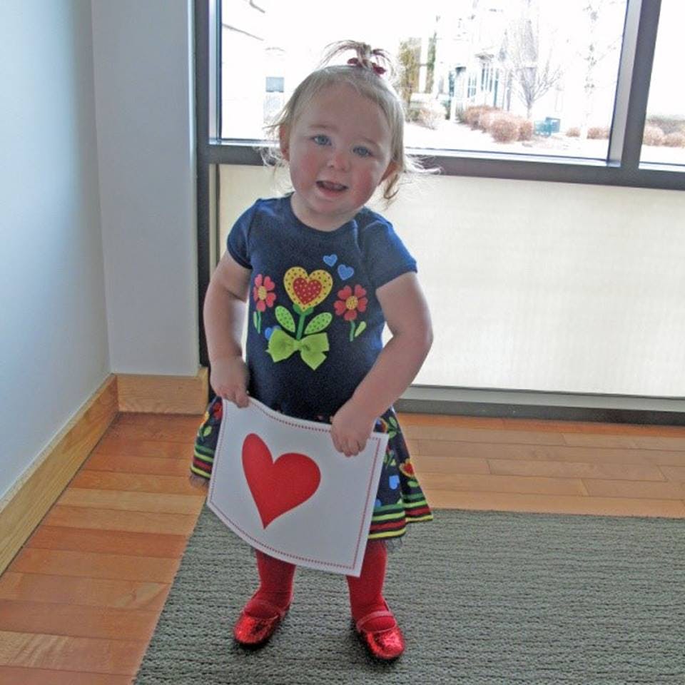 Child holding a white square with a red heart