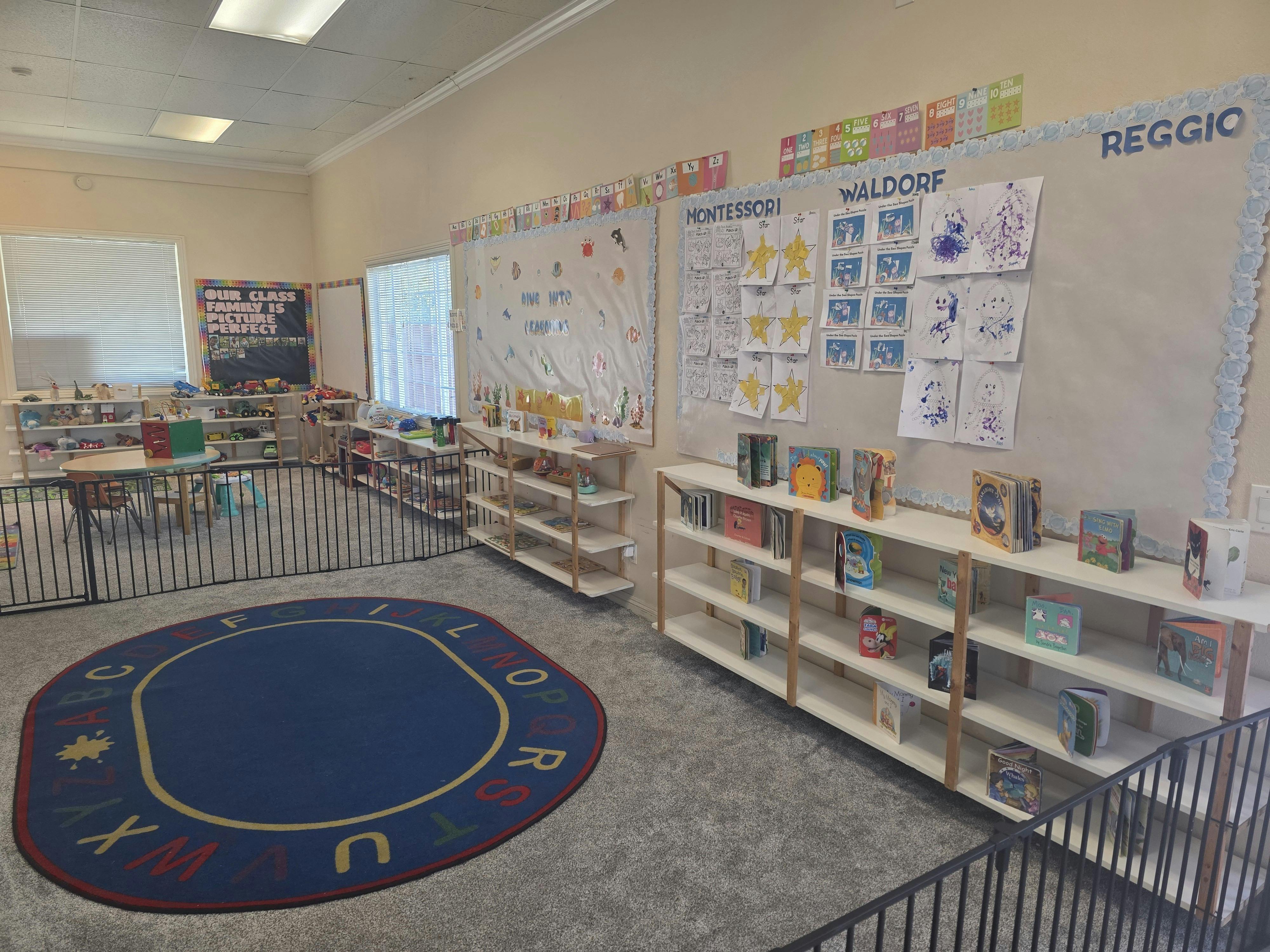 Classroom with child-sized furniture, shelves of toys and books, and a colorful alphabet rug