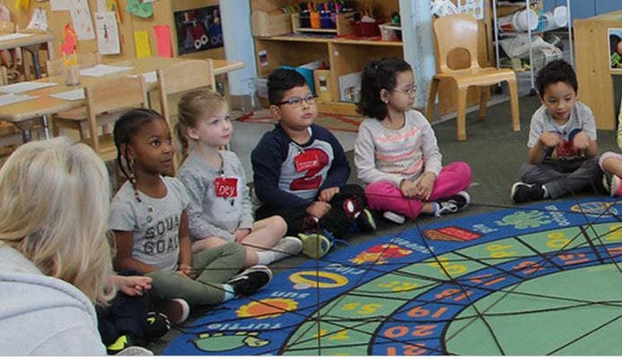 Adult and children sitting on a rug in a classroom