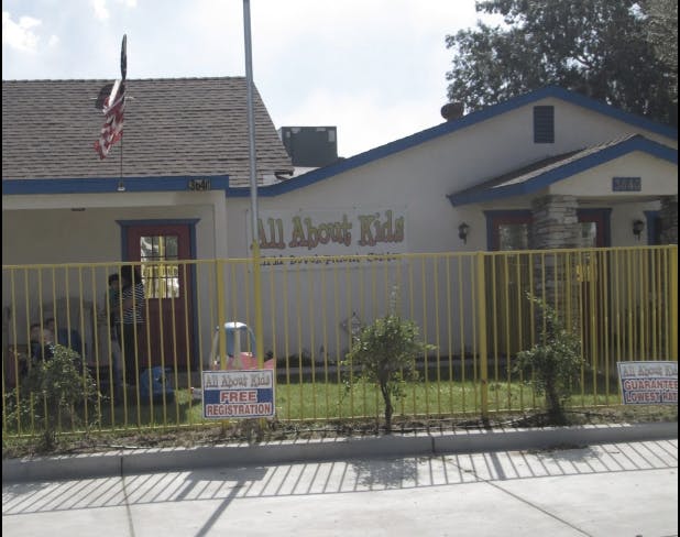 Building with "All About Kids" sign behind a yellow fence