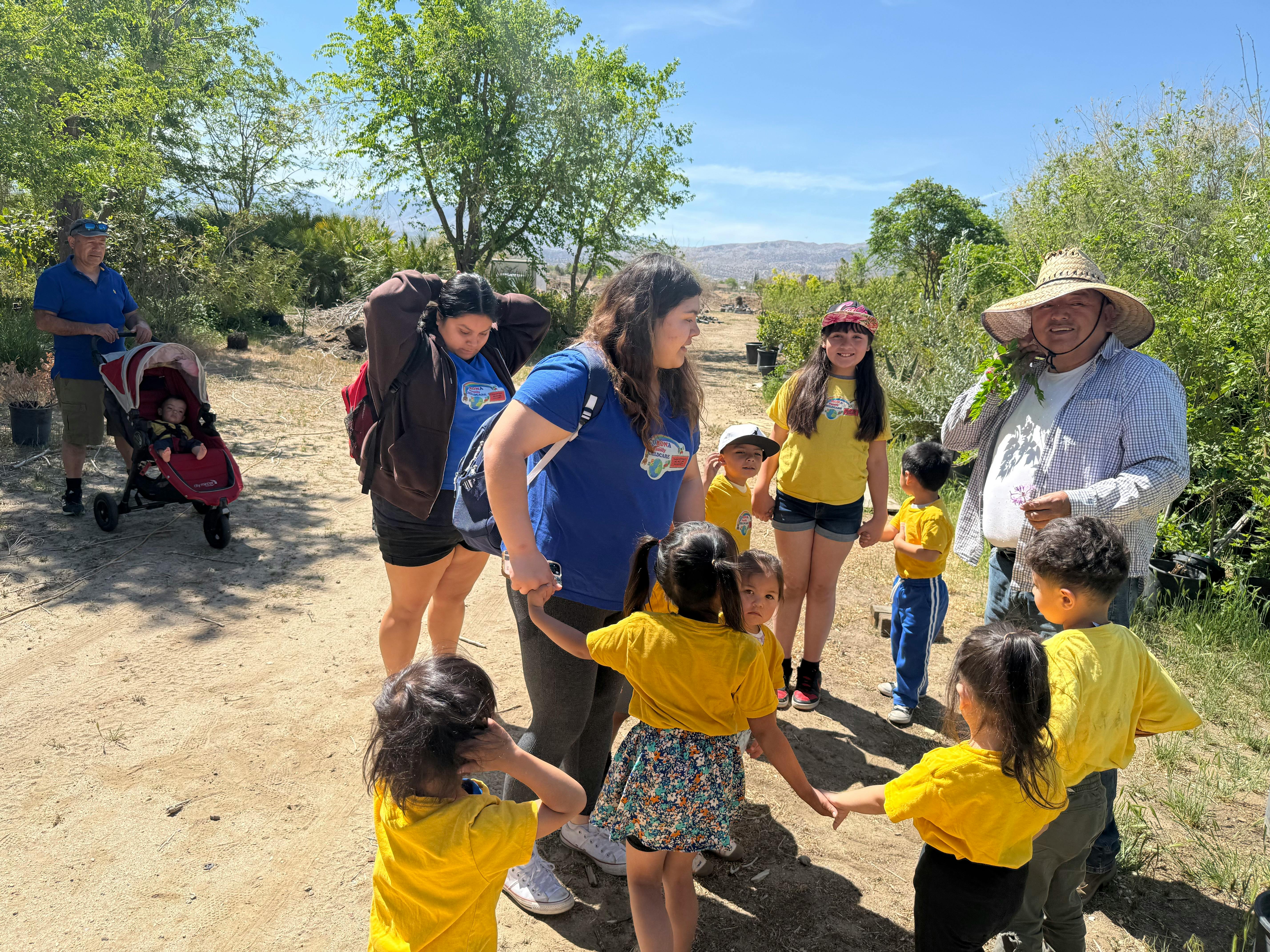 People and children gathered outdoors on a dirt path