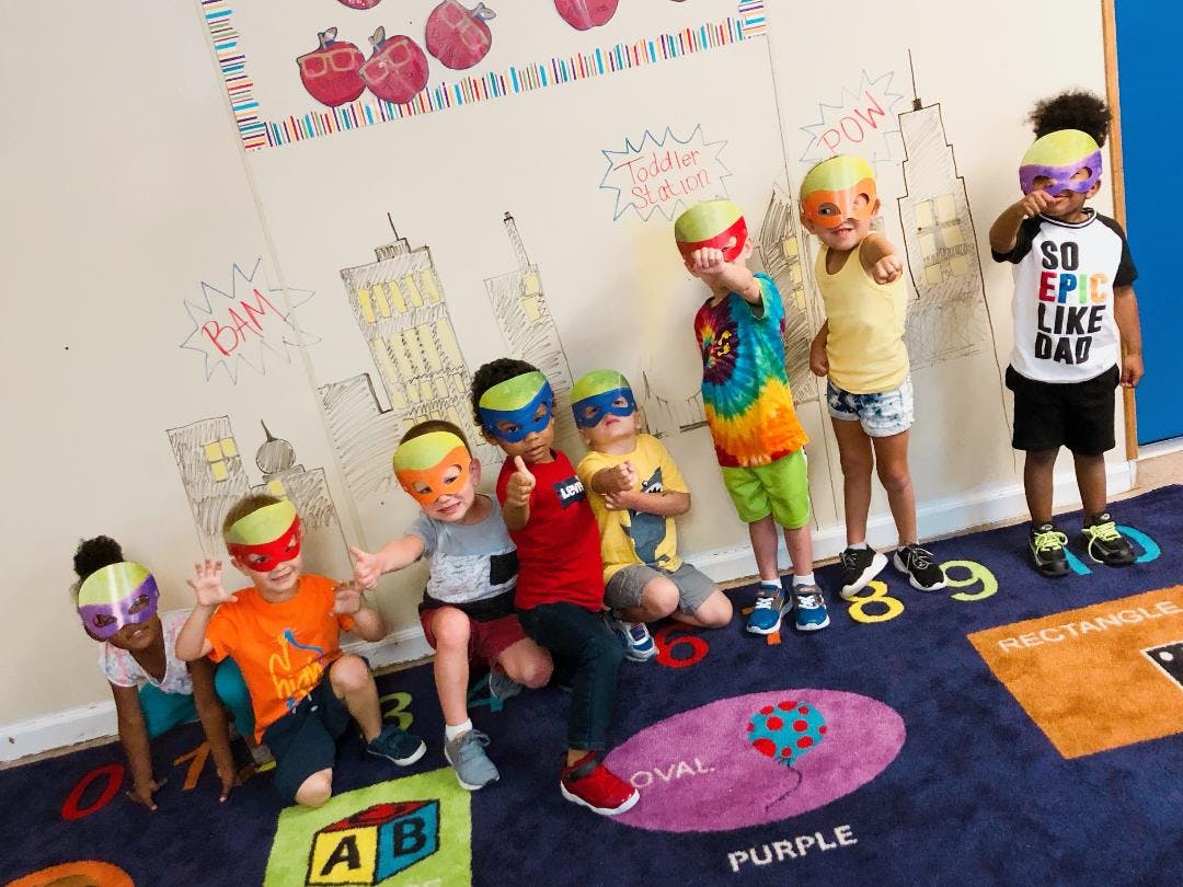 Group of children wearing superhero masks in a classroom