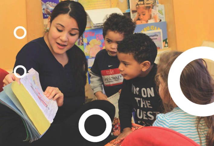 Person reading a book to three children