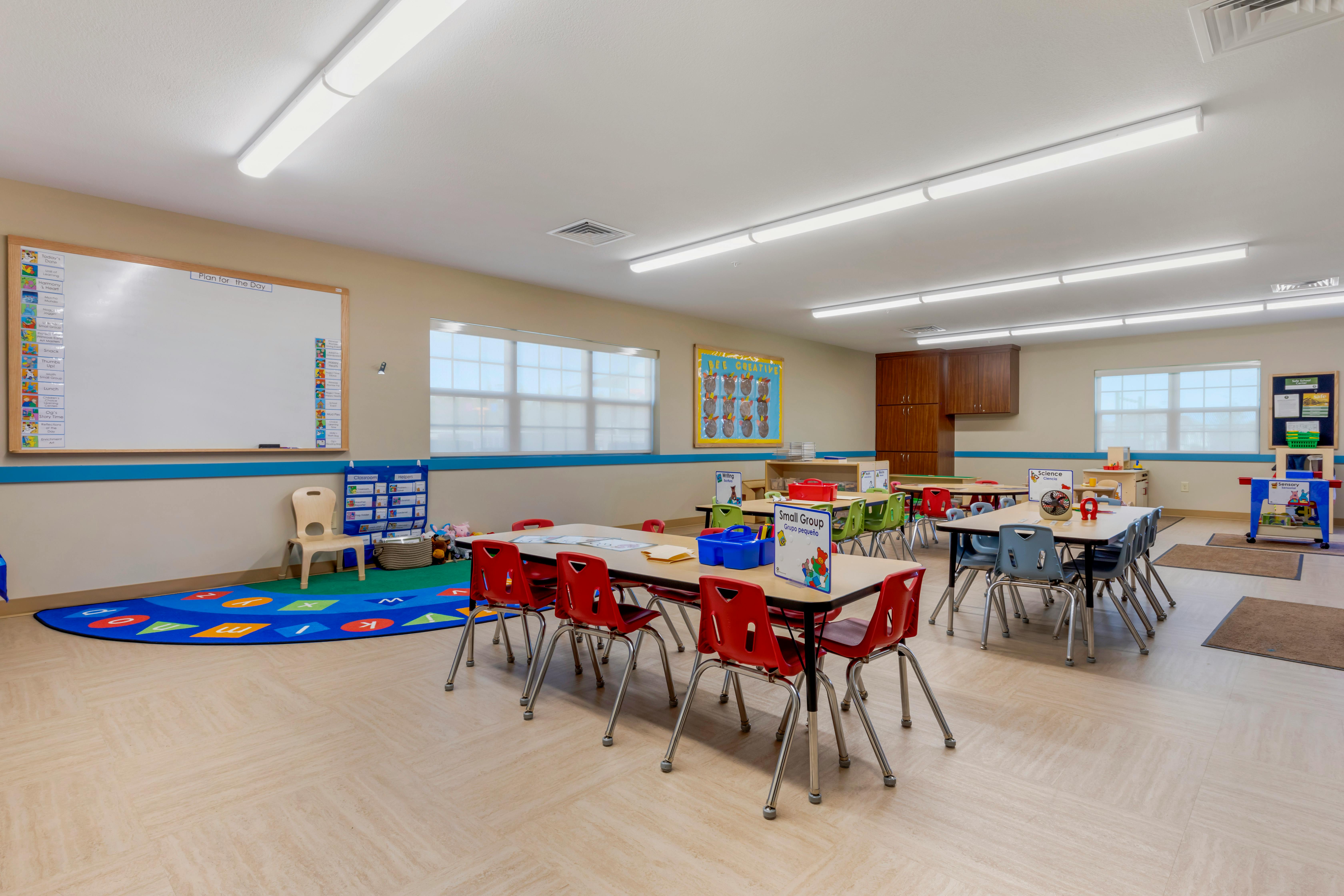 Classroom with small tables and chairs, a whiteboard with "Plan for the Day" written on it