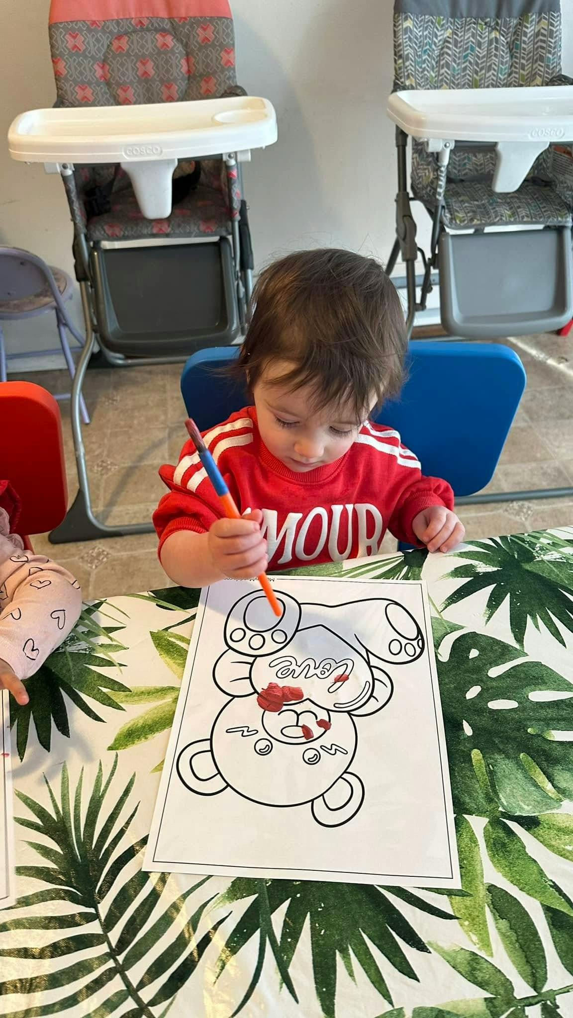 Child coloring a picture of a bear with a paintbrush