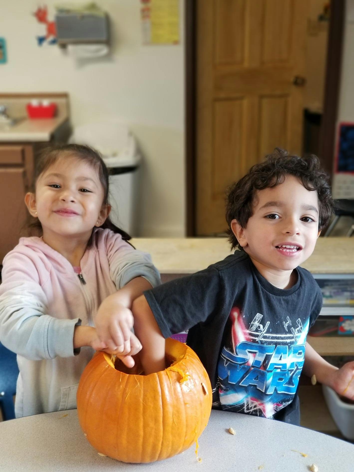 Two children carving a pumpkin