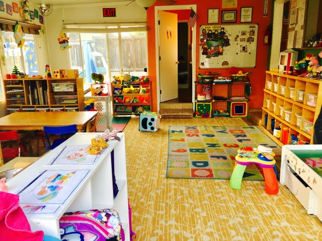 Playroom with alphabet rug, toys, and small tables