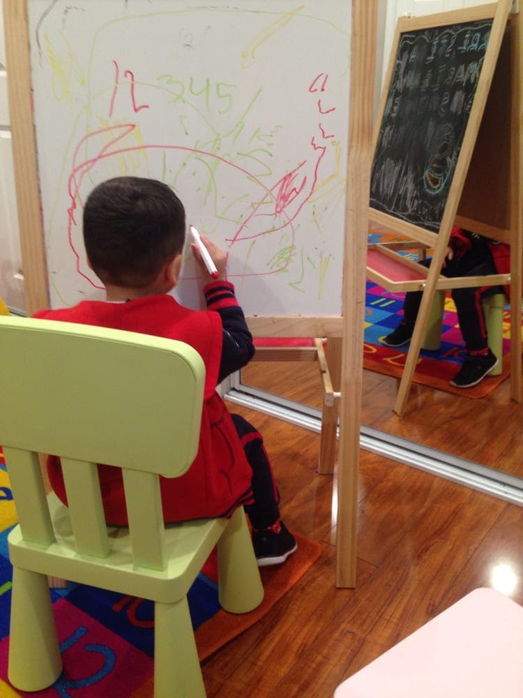 Child sitting on a chair drawing on a whiteboard