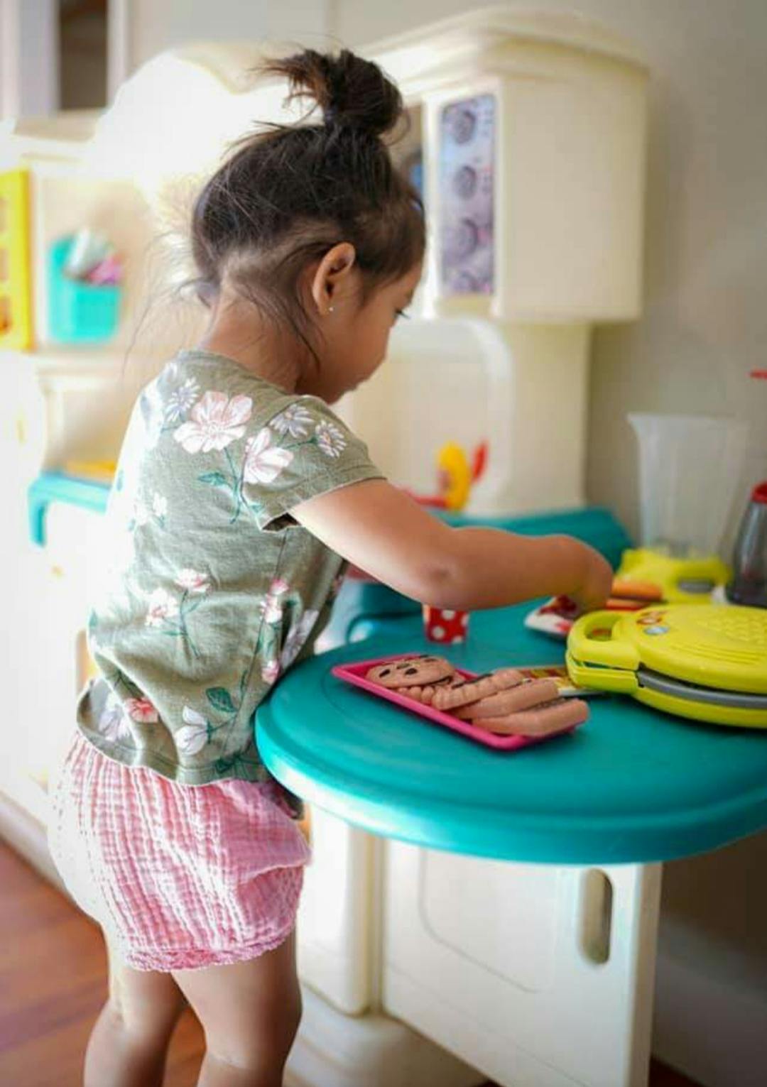 Child playing with toy kitchen set and toy food