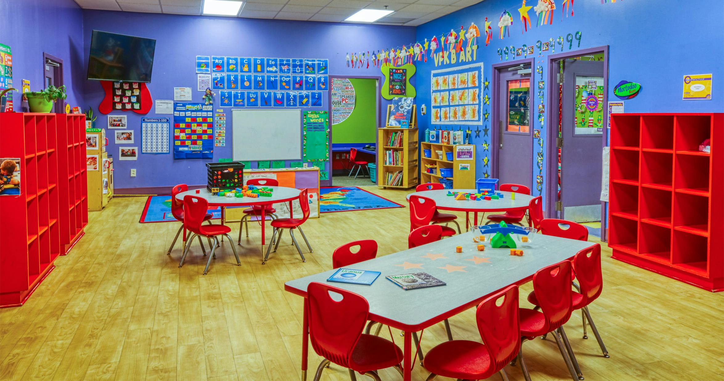 Classroom with tables, red chairs, and colorful decorations