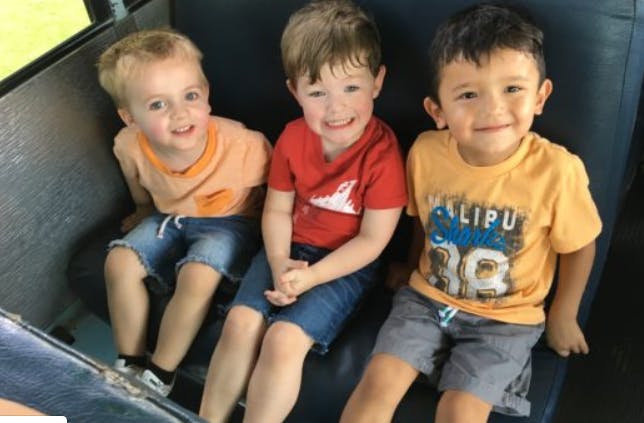 Three children sitting on a bus seat