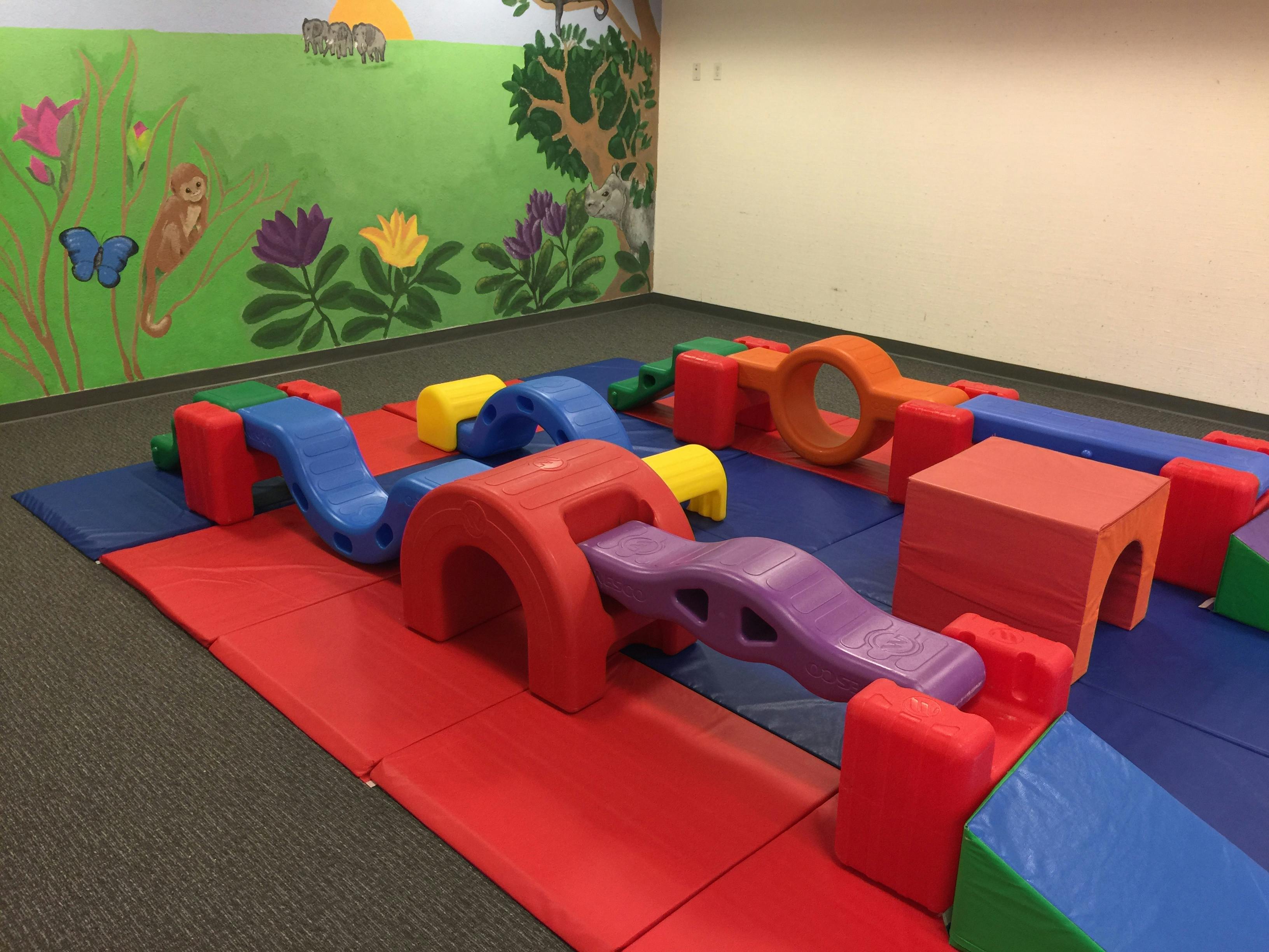 Indoor soft play area with colorful foam shapes and mats